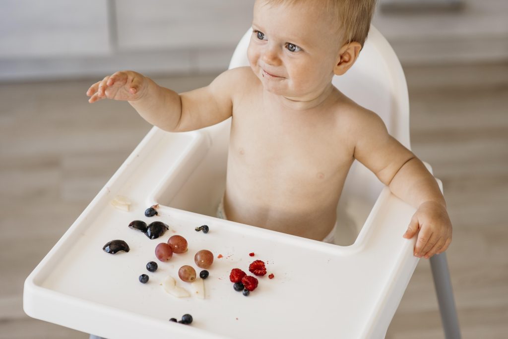 high angle cute baby highchair choosing what fruit eat